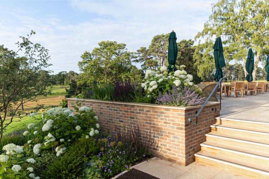 Steps descend next to wall retaining flower bed.