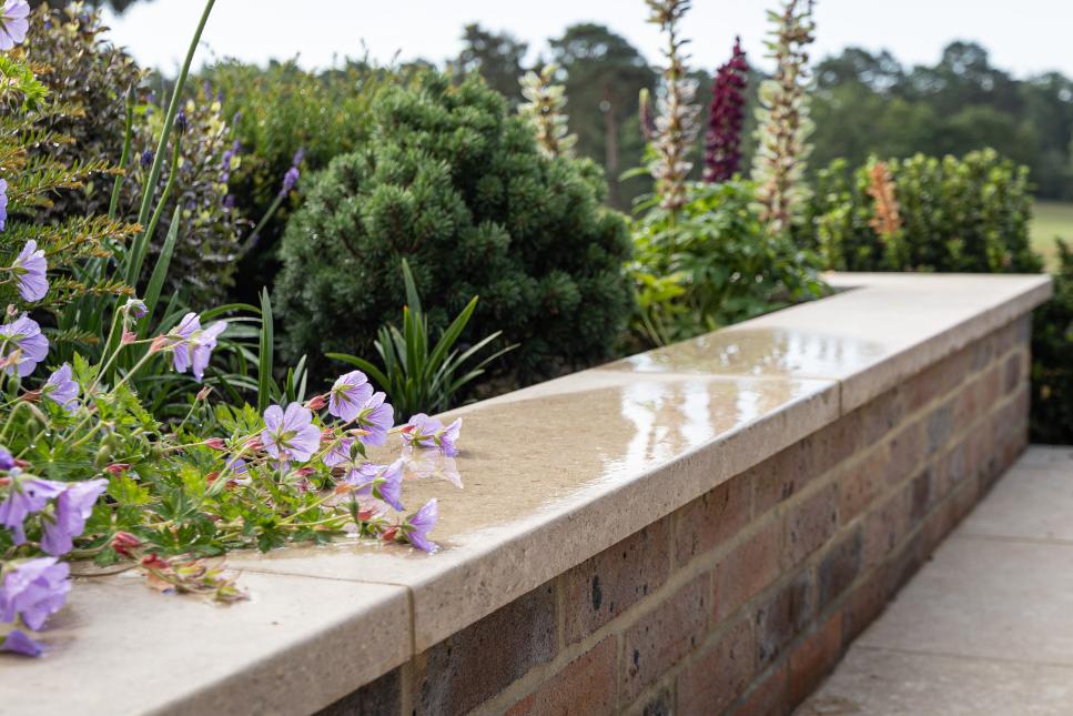 Egyptian Beige coping with pencil round edge profile on top of brick wall.