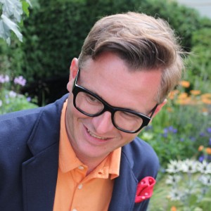 Head shot of garden designer Frederic White against a colourful blurred flower border.
